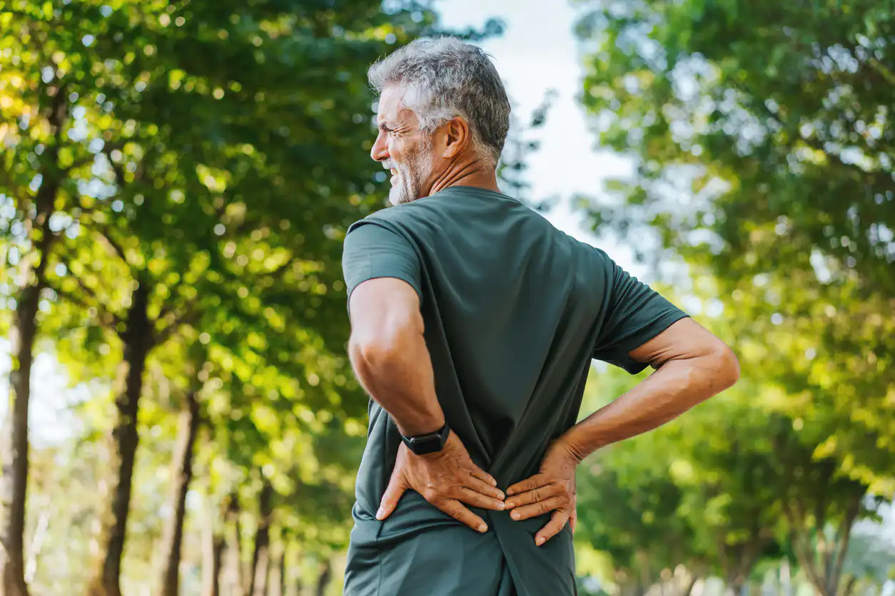 Älterer Mann mit Rückenschmerzen im Park