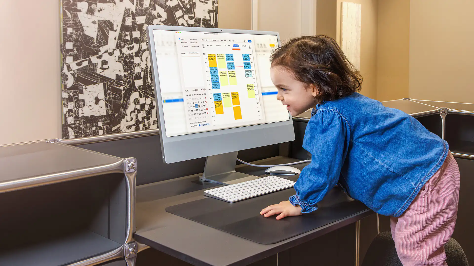 Kleinkind vor Desktop-Computer mit Kalenderanzeige